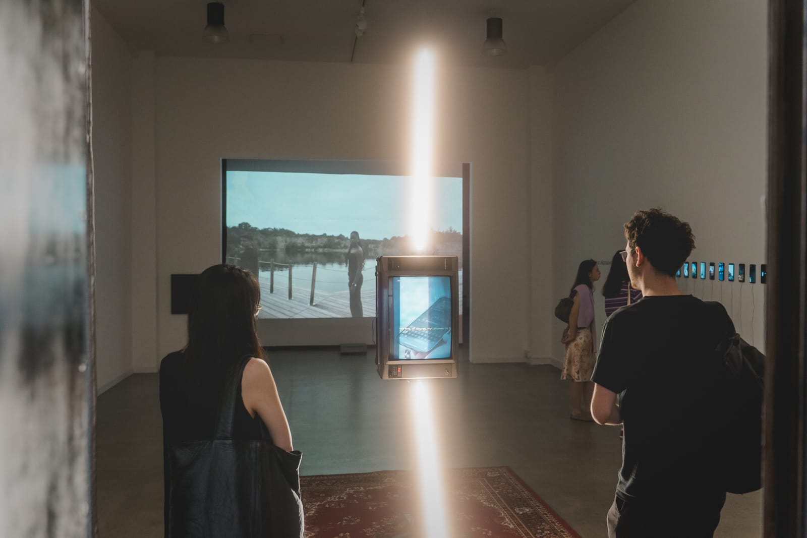Visitors in a gallery watching a projected video installation