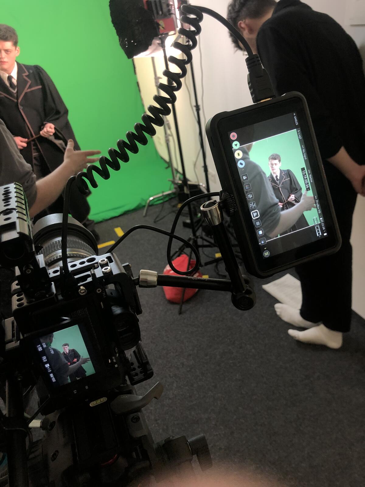 Camera rig with a field monitor in front of a green screen, an actor in costume in the frame