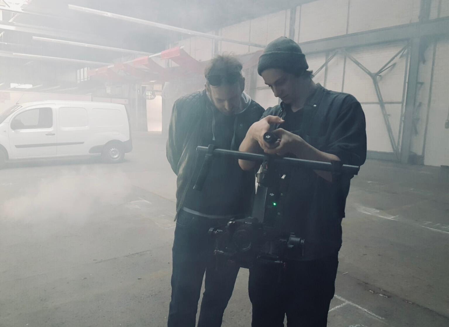 Two crew members checking a gimbal shot in a smoke-filled warehouse