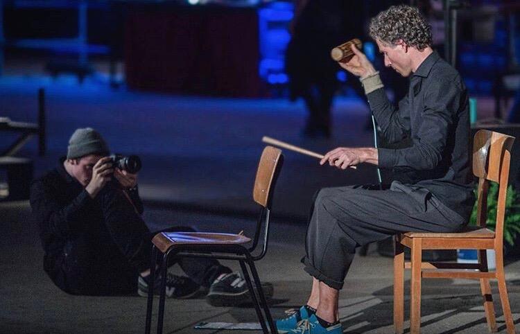 Photographer crouched on the floor shooting a percussionist on a chair at night