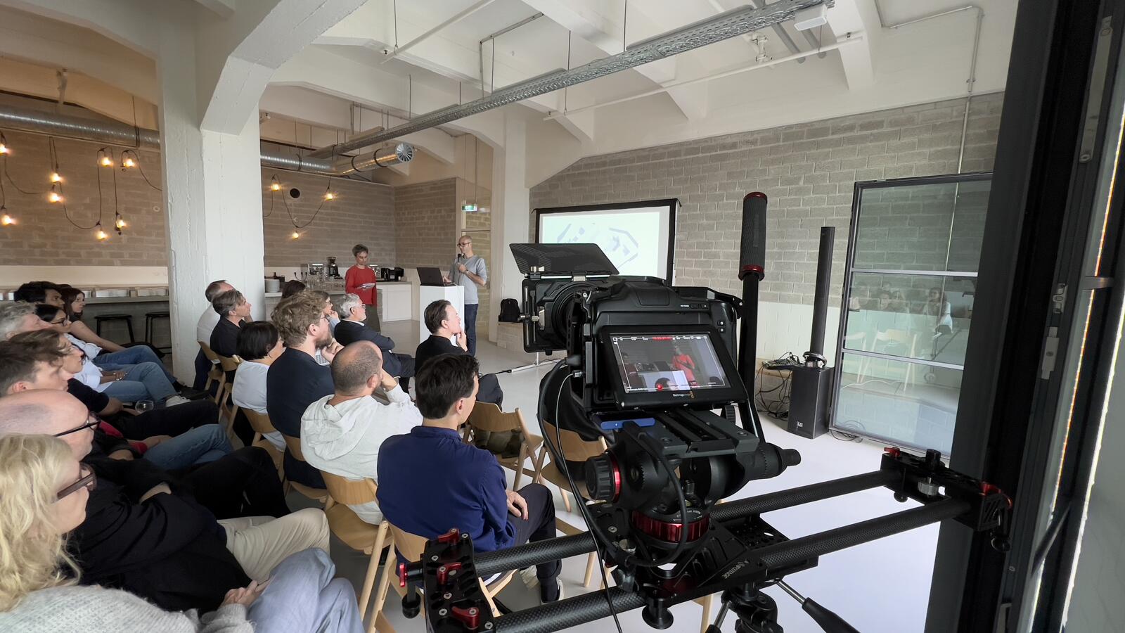 Camera on a slider filming a talk in a packed loft space