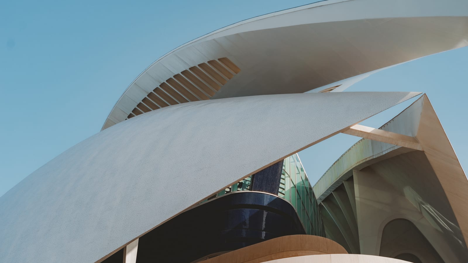 Sweeping white roof of a modern building against a blue sky