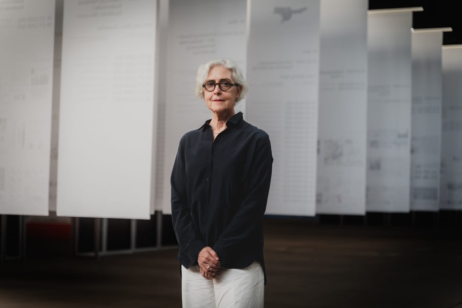 Portrait of a woman with glasses in front of white panels