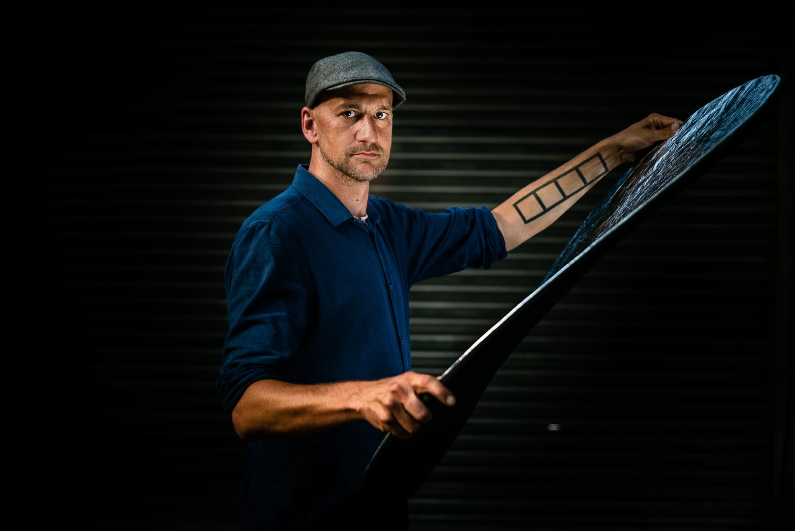 Man holding up a large pane against a dark backdrop