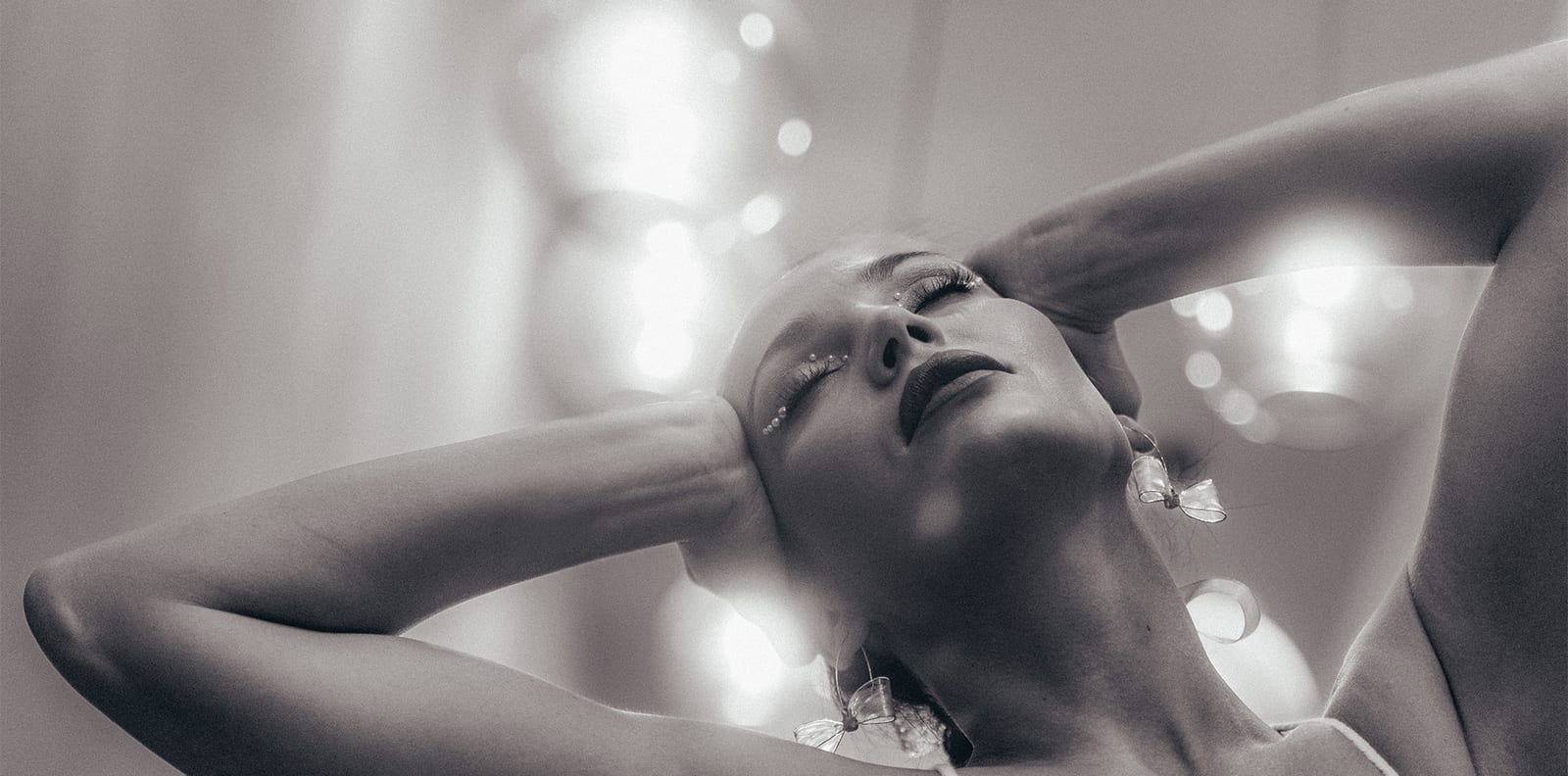 Woman with raised arms in soft, glittering white light