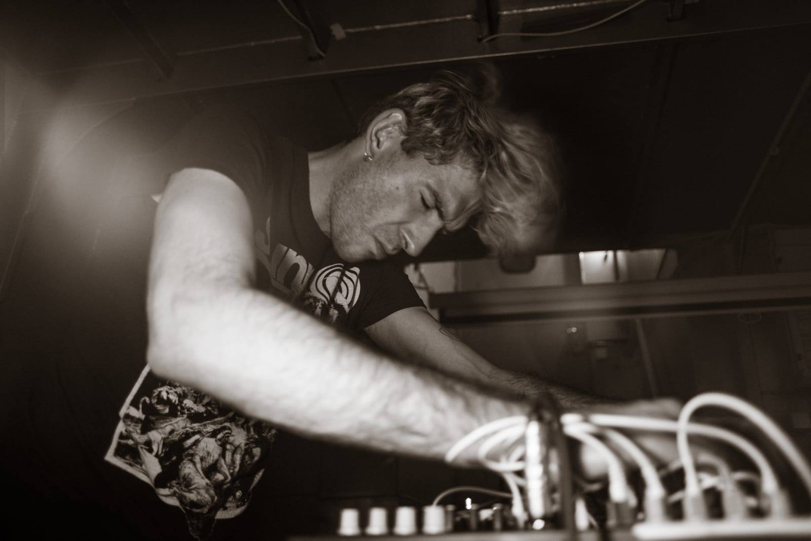 Musician bent over a mixing desk, in sepia